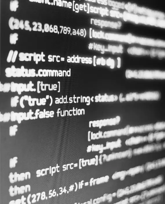 Close-up of a computer screen displaying lines of code in white text on a black background, with certain code elements in focus and others blurred.